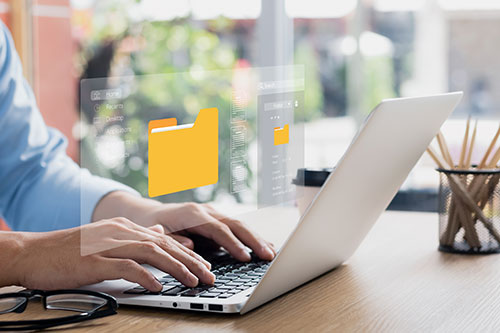 Man on laptop with image of file folder floating beside him
