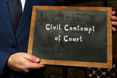 Man holding sign that reads "Civil Contempt of Court"