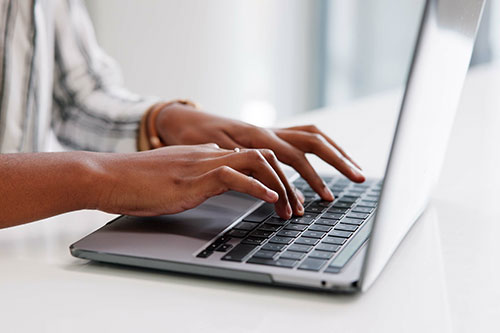 Hands typing on laptop